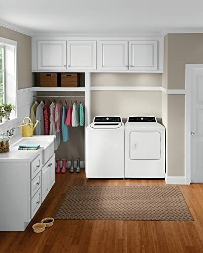 Laundry room with washer, dryer, hanging clothes, and storage cabinets