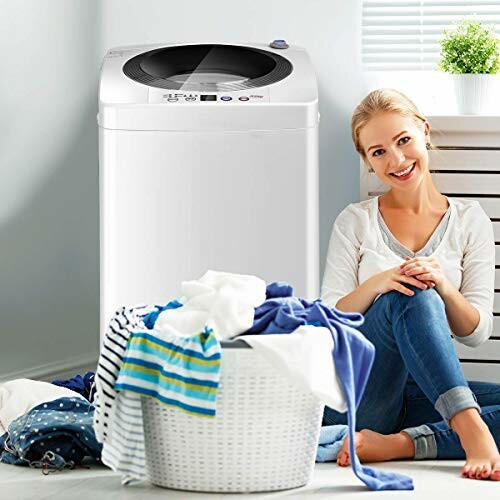 Smiling woman sitting next to a washing machine with a basket of laundry.